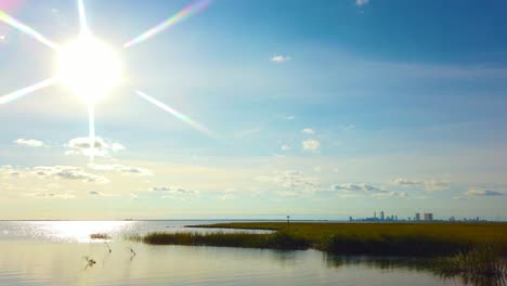 4K-Schwenk-Von-Links-Nach-Rechts-Von-Der-Sonne-Im-Linken-Mittelrahmen-Zur-Skyline-Der-Atlantikstadt-In-Der-Ferne-Im-Mittelrahmen-An-Einem-Schönen,-Meist-Sonnigen-Tag