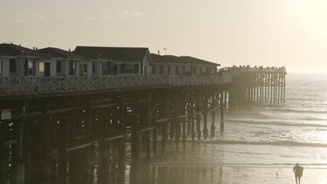 pacific beach california pier sunset with waves crashing on beach - slow motion from right side of pier