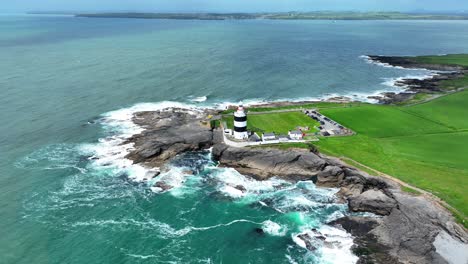 Irlands-Epische-Orte,-Landschaftsdrohne-Kreist-Direkt-über-Dem-Hook-Head-Leuchtturm-Vom-Meer-Aus-Und-Gibt-Den-Blick-Auf-Die-Hook-Halbinsel-In-Wexford-Frei