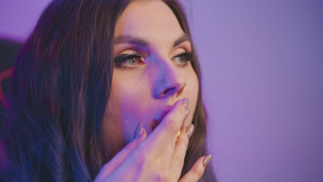 close up of female eating popcorn under vibrant purple studio lighting focus on glossy lips and crisp kernels moving to mouth, dramatic eyeliner accent and cozy gaming chair ambiance with neon glow