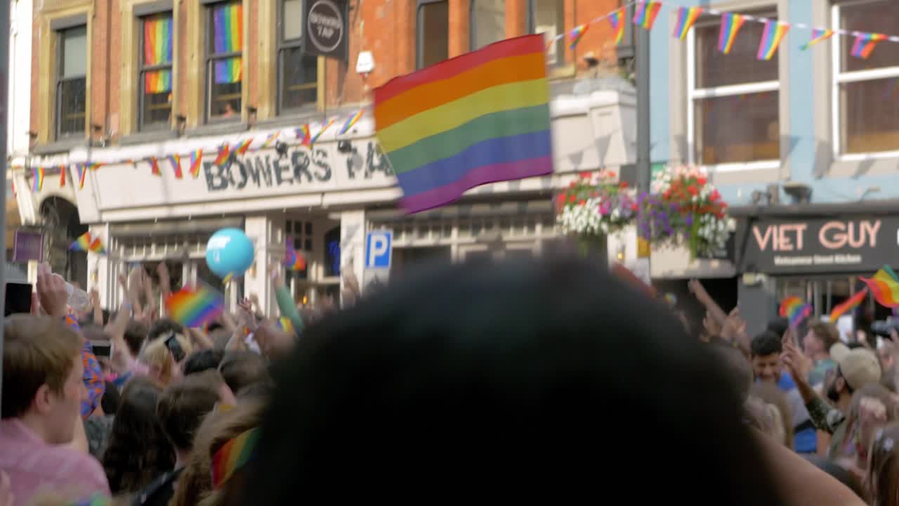 Leeds Pride LGBTQ Festival 2019 waving flag tracking flag shot as it waves pride flag rainbow flag with people dancing 4K 25p