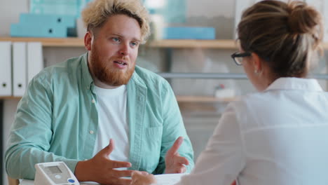 Overweight-Man-Complaining-about-Health-to-Doctor-in-Clinic