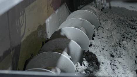 mixing fins turning the cement inside a concrete paving machine