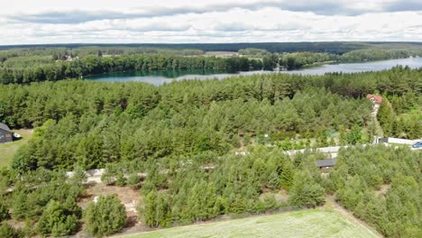 High-altitude-flight-over-of-Lake-Jezioro-Gwiazdy-and-Borowy-Młyn-village-in-Kaszuby,-Pomeranian-Voivodeship,-Poland