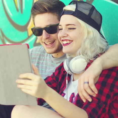 laughing young hipster couple checking a tablet