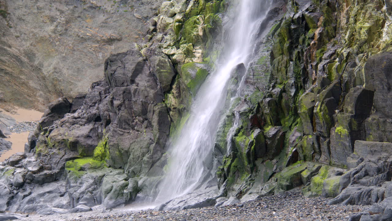 mid shot of base of Tresaith waterfall flowing over rocks
