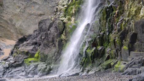 mid shot of base of tresaith waterfall flowing over rocks