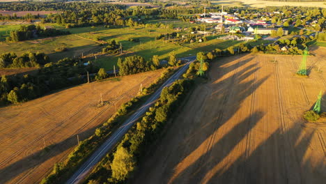 Caminos-Que-Conducen-A-Una-Pequeña-Ciudad-Rural-En-La-Tarde-Soleada,-Vista-Aérea-De-Drones