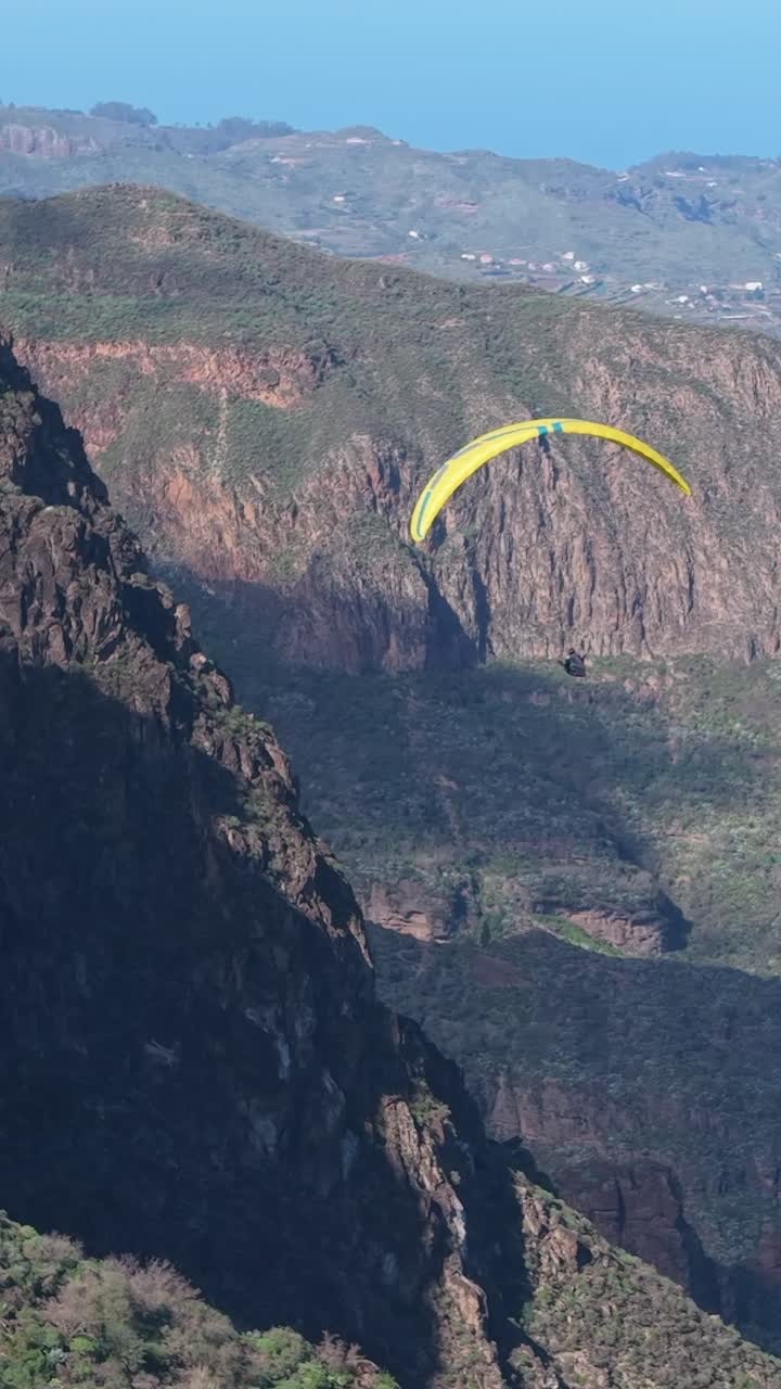 Mann flyr paraglider over et vulkansk landskap på Gran Canaria, Kanariøyene