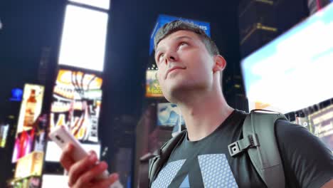 man using smartphone in times square at night