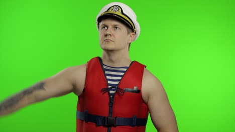 muscular sailor man works as lifeguard at beach salutes with hand to camera