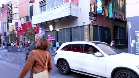 people walking and car crossing street