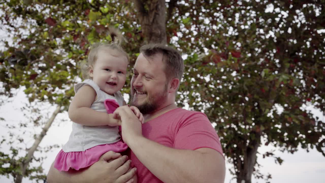 Close-up de pai e filha brincando juntos. O jovem pai gira a filha em suas mãos, rindo e brincando. O conceito de uma família feliz