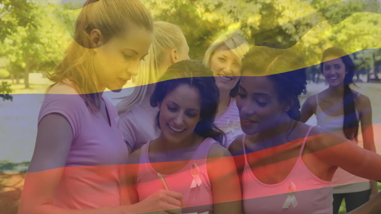Gruppo di donne che indossano magliette rosa sopra un'animazione della bandiera colombiana che sventola