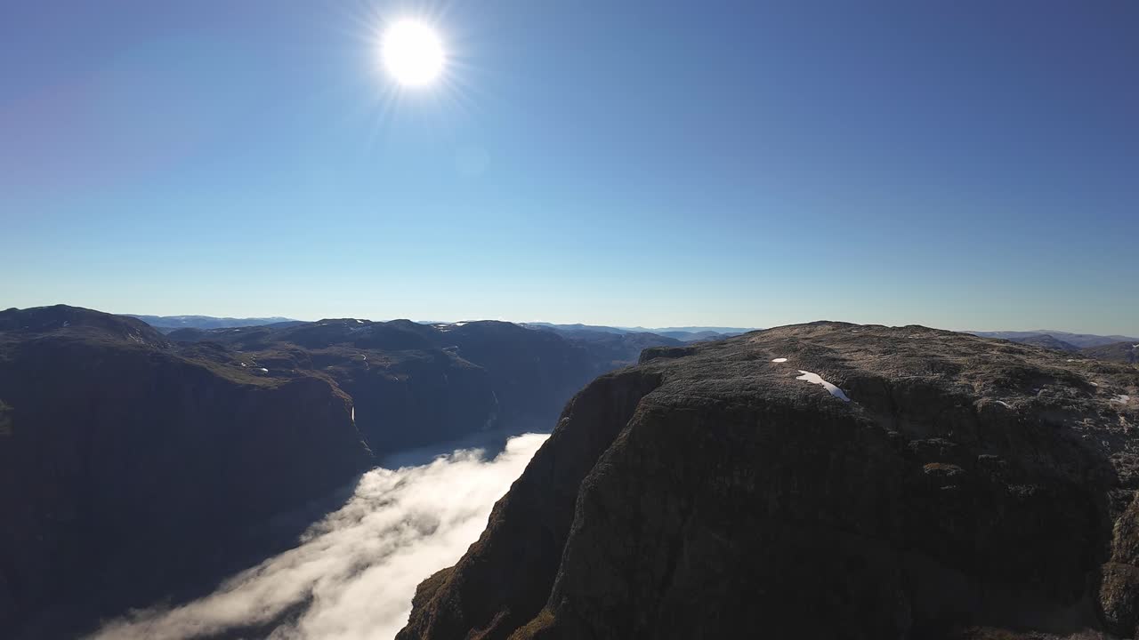 Aerial view over Naeroyfjord with cloud inversion below, moving toward Fetanipa mountain near Gudvangen. Sunny grand UNESCO landscape