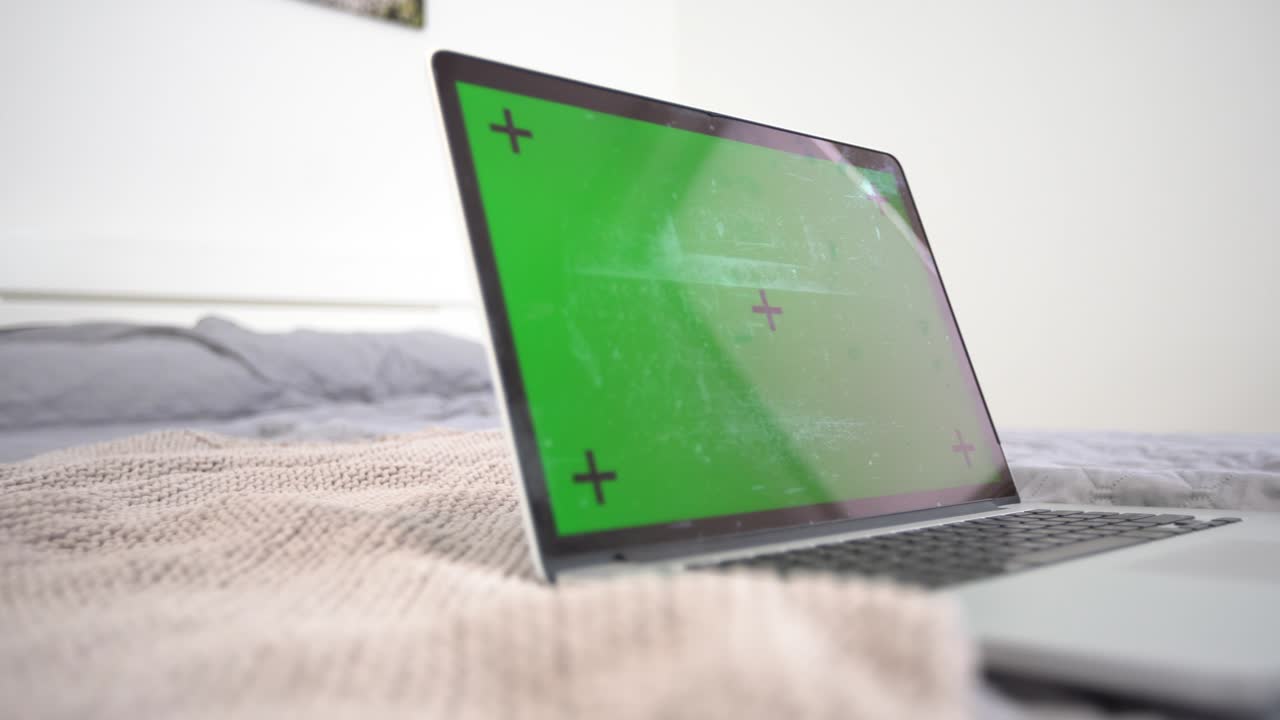 una computadora portátil de pantalla verde sentada en un escritorio de trabajo en casa junto a una lámpara de escritorio.