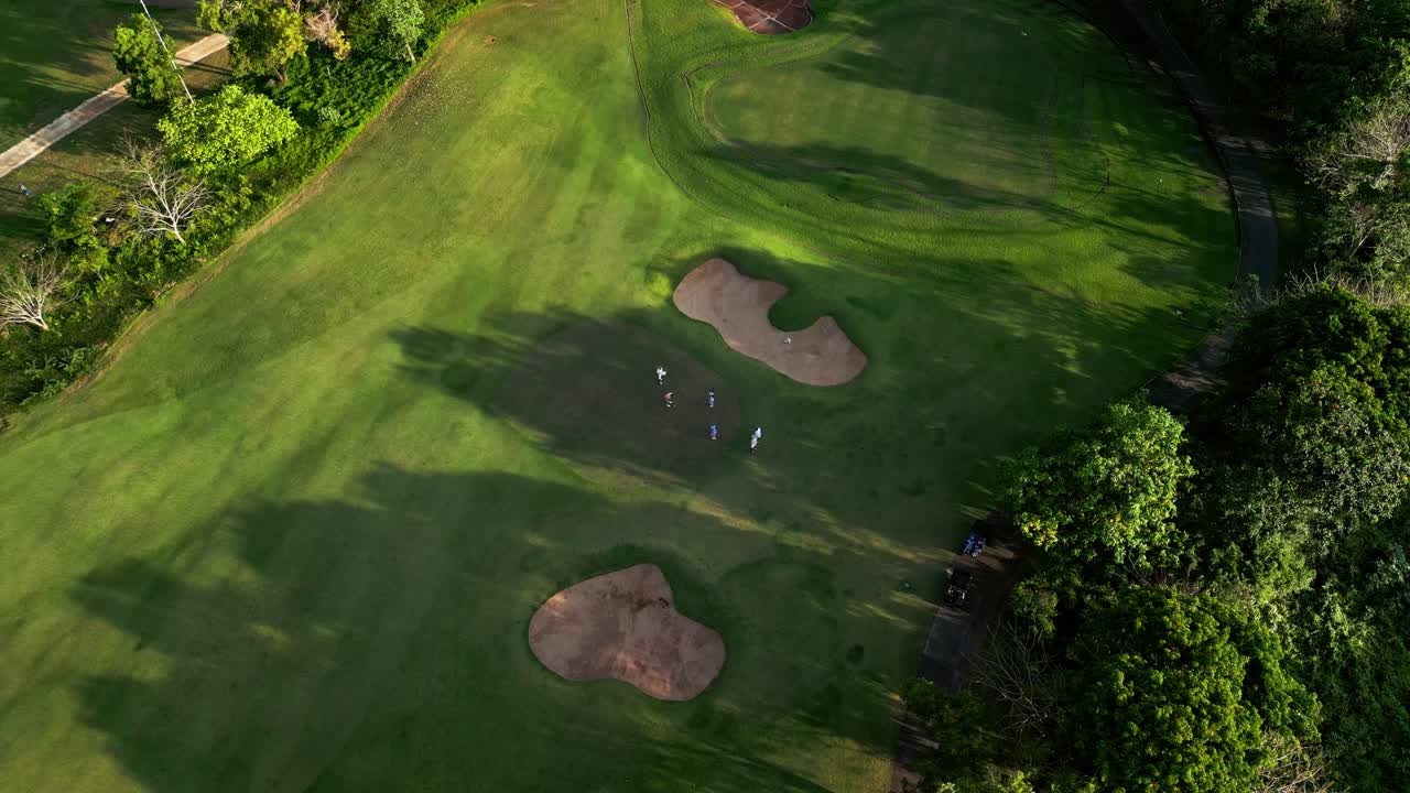 Drone footage revealing a vibrant Bali golf resort surrounded by greenery, sand traps, and tropical trees, capturing a perfect blend of sport, leisure, and island tranquility