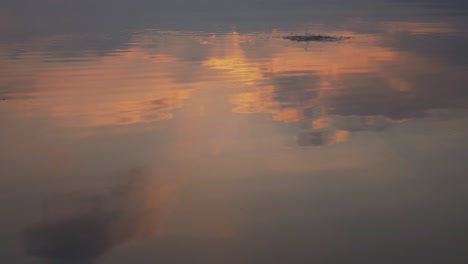 Slow-motion-rock-splash-into-water-idyllic-sunset-view-reflection