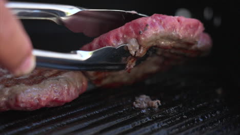 Slow-motion-close-up-shot-of-a-burger-patty-being-turned-over-on-a-BBQ