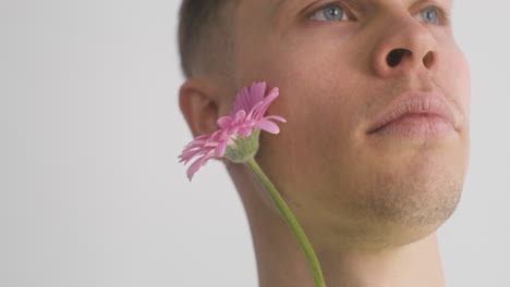 close up view of handsome man holding pink flower