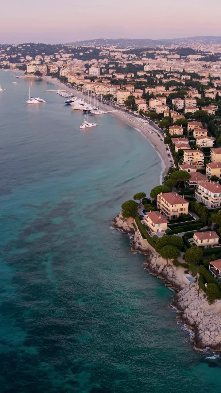 Video aereo che cattura un mozzafiato paesaggio urbano costiero al tramonto, mostrando acque turchesi.