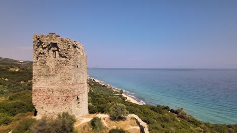 Clip-Aéreo-De-Drones-Avanzando-Hacia-Una-Antigua-Torre-En-Ruinas-Y-Sobre-Una-Hermosa-Playa-En-Kavala,-Macedonia,-Grecia