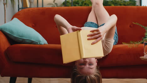 Mujer-Joven-Leyendo-Un-Libro-Interesante-Pasando-Páginas-Sonriendo-Disfrutando-De-La-Literatura-Descansando-En-El-Sofá