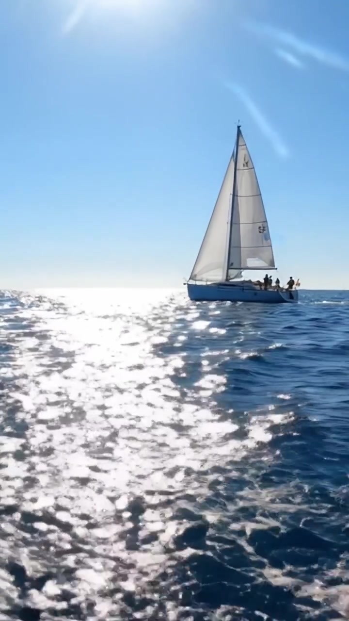 Una Serena Aventura en Velero: Una Vista Cautivadora de un Velero Deslizándose sobre Aguas Azules Brillantes Bajo un Sol Radiante con un Cielo Perfecto