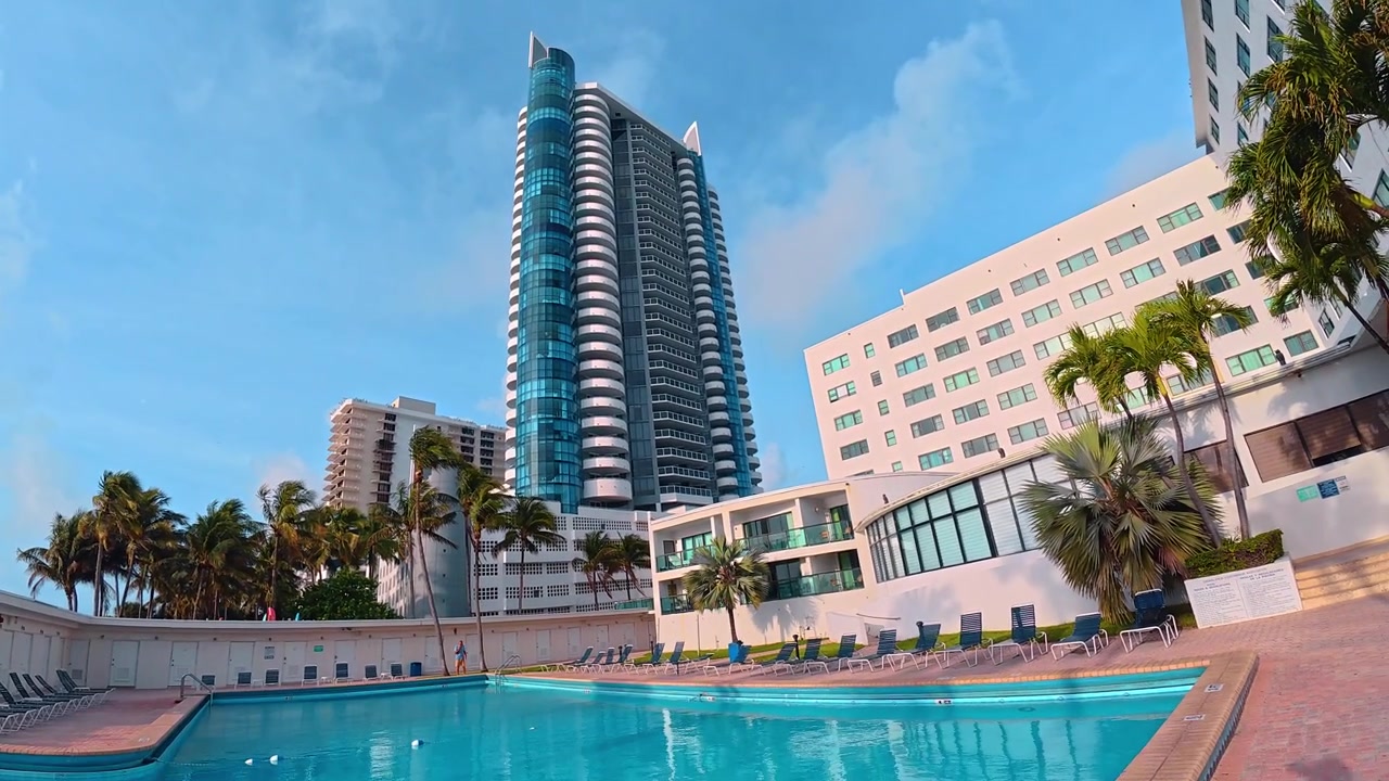 Grattacieli e palme a Miami Beach. Vista verso l'alto di moderne facciate in vetro e edifici bianchi contro il cielo con palme illuminate dal sole