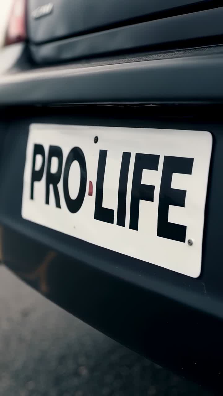 Vertikal video: Opptak starter, kamera nærmer seg parkert bil bakfra, og avslører detaljer om PRO·LIFE-skiltet