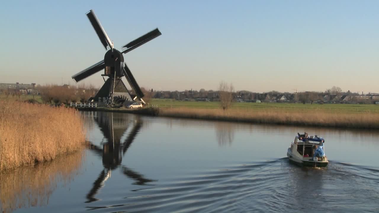 풍차가 근처에 있는 네덜란드의 운하를 따라 보트가 이동합니다. 6