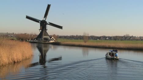 a boat moves along a canal in holland with windmills nearby 6