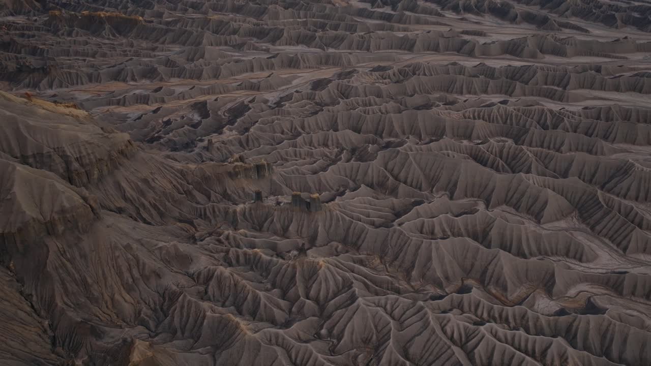 Shadowed desert badlands ridges forming textured erosion patterns near Factory Butte Utah, drone
