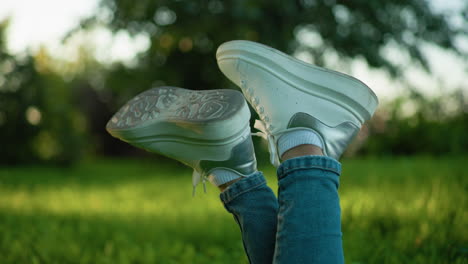 close-up of white sneakers on crossed legs in a grassy field with a soft bokeh background, the relaxed pose and casual attire create an outdoor leisure vibe surrounded by greenery