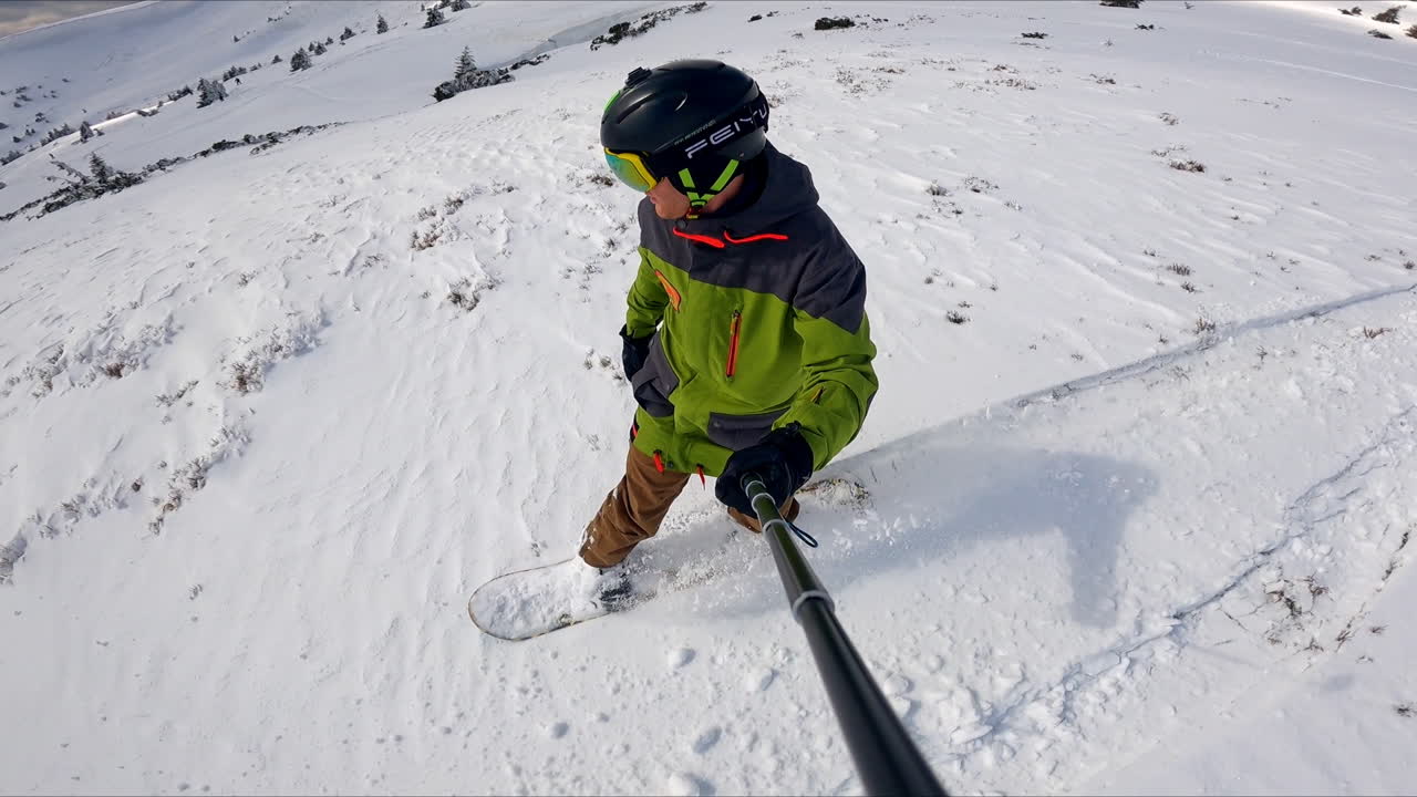 Selfie of the snowboard ride in the mountains. Sportsman quickly goes down the snowy slope.