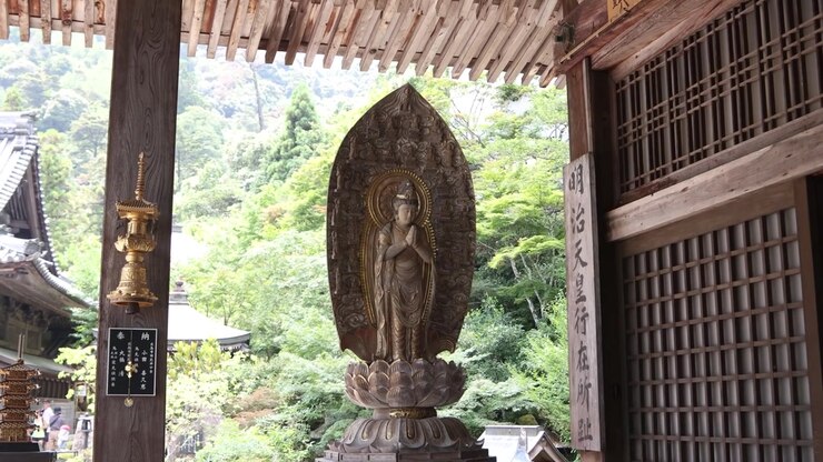 Traditionel trætempelindgang, der indrammer en hellig statue under Kangen Sai-festivalen på Miyajima-øen, Hiroshima, Japan