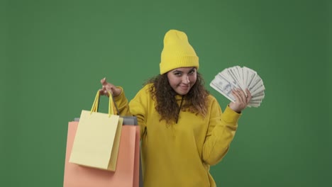 woman holding dollar banknotes and showing her shopping bags