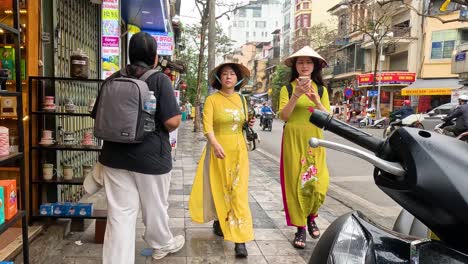 two women in áo dài walking on city sidewalk