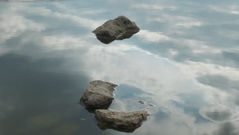 river or lake landscape with reflections of cloudy sky in water. ripple surface of calm water at evening or morning time