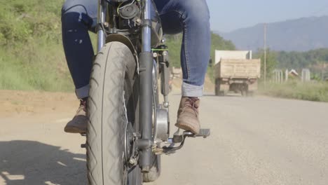 man riding a vintage motorcycle on a country road
