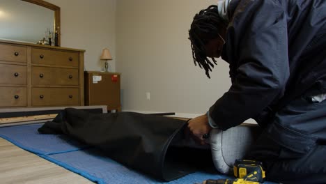 man assembling grey couch in a room