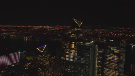 Group-of-illuminated-high-rise-buildings-on-Hudson-River-waterfront.-Night-cityscape-in-background.-Manhattan,-New-York-City,-USA