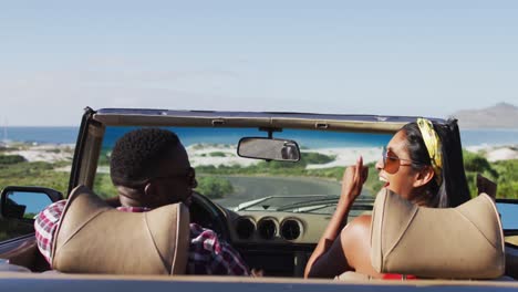 African-american-couple-raising-their-arms-in-the-air-while-sitting-in-the-convertible-car-on-road