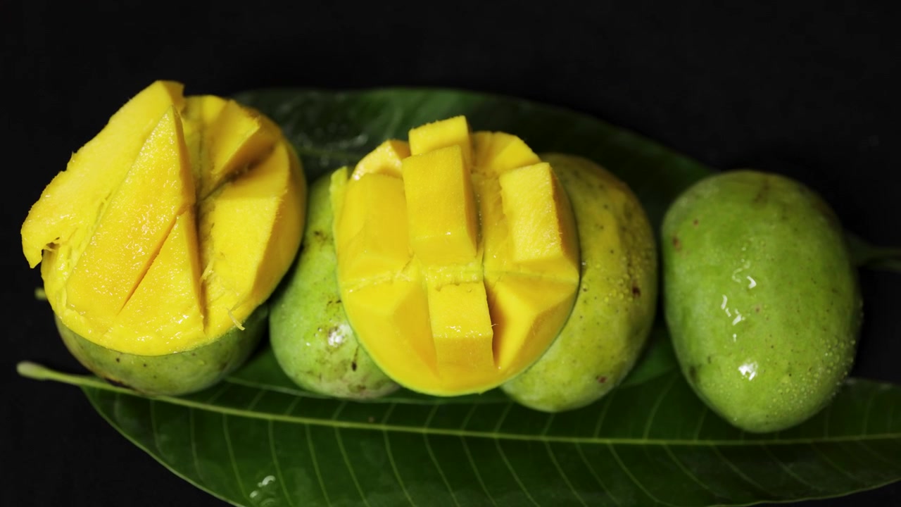 Saftig Malda-mangofruktutstilling med skivede mangoterninger og hele modne mangoer