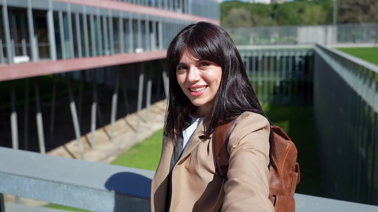 Giovane donna felice che registra un video selfie nel campus universitario.