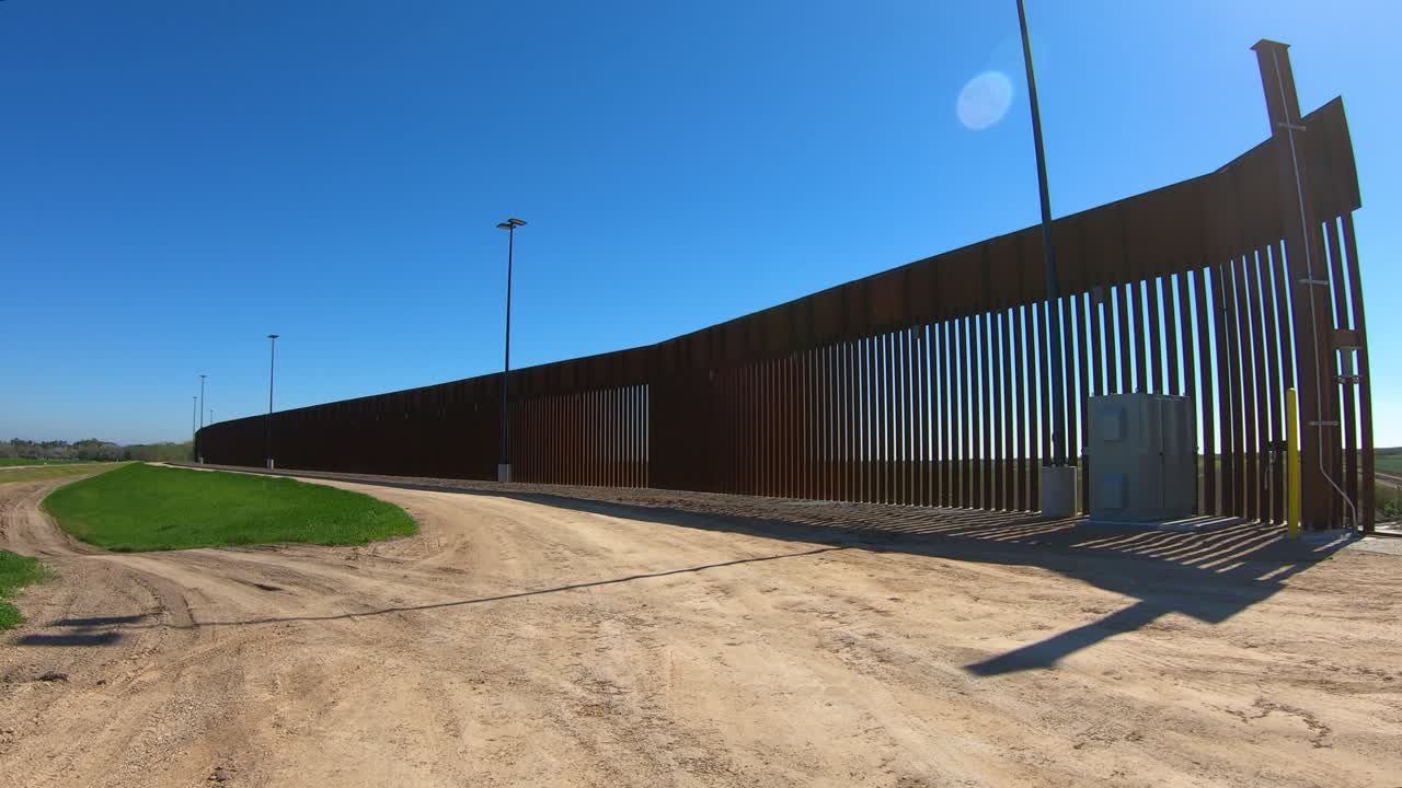 pov trasero conduciendo en la vía de servicio lejos del muro fronterizo entre estados unidos y méxico
