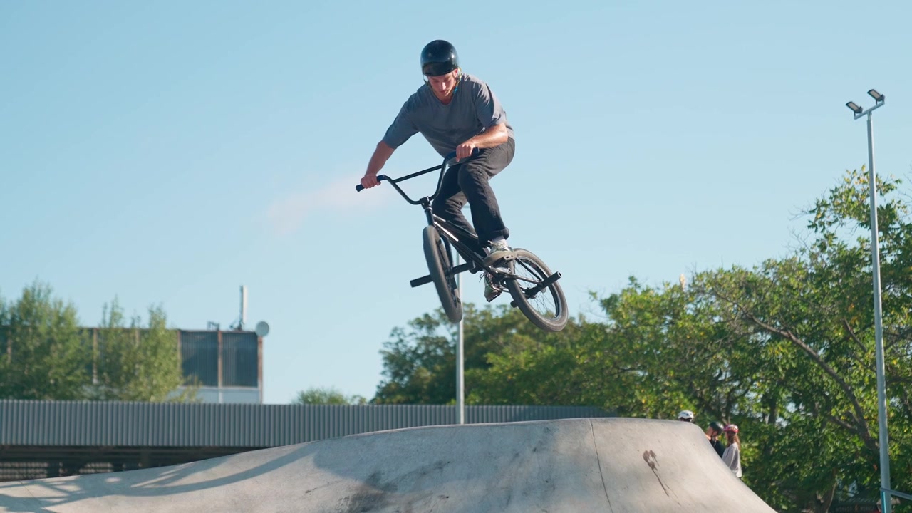 Giovane uomo in BMX che salta su una rampa in uno skatepark