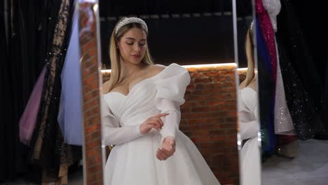 a woman in a white wedding dress looks at herself in a mirror