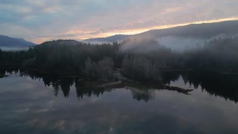 aerial view of secluded scenic lake and foggy trees at sunrise