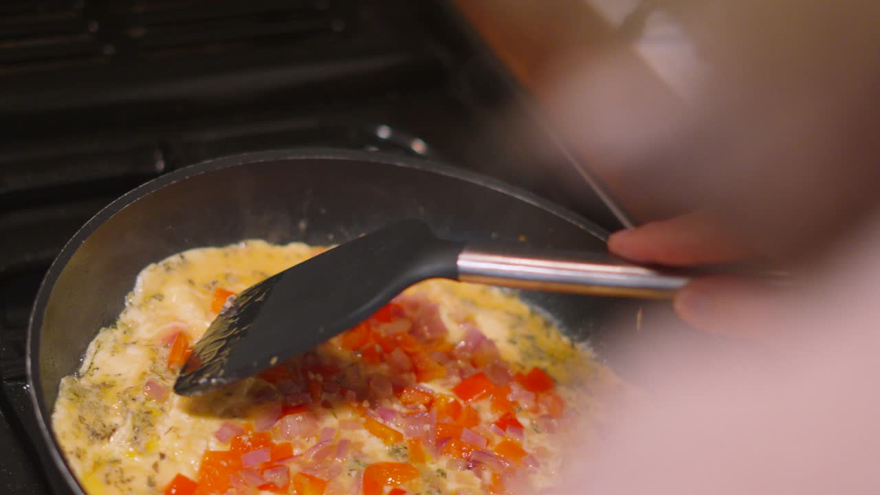 Omelette with Peppers, Onions, Cheese Being Cooked in Frying Pan with Female Chef Using Turner to Ensure Even Cooking on Edges